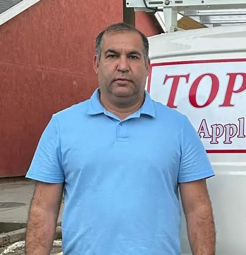 Top Town technician Masood standing next to the company van